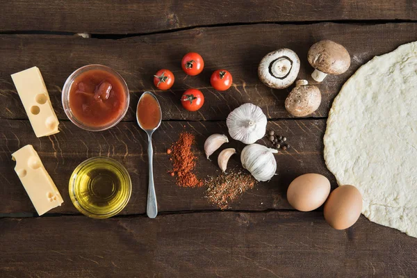 Zutaten für die Zubereitung von Pizza auf hölzerner Tischplatte — Stockfoto