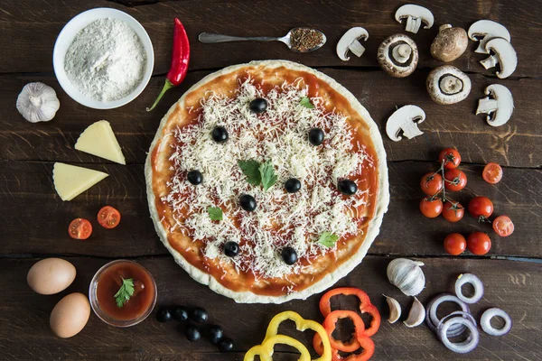 Pizza avec divers ingrédients sur la table — Photo de stock