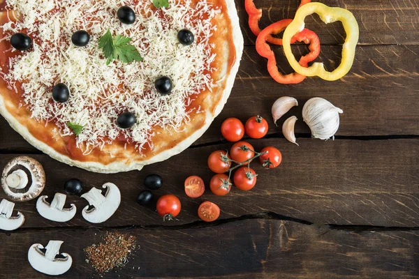 Pizza with cheese and vegetables on wooden tabletop — Stock Photo