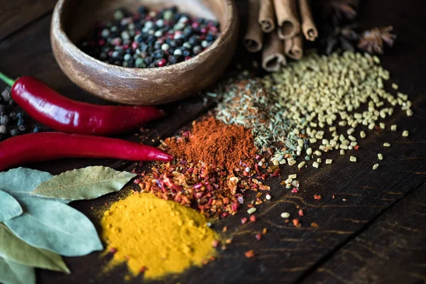 Pepper in bowl with scattered herbs and spices — Stock Photo