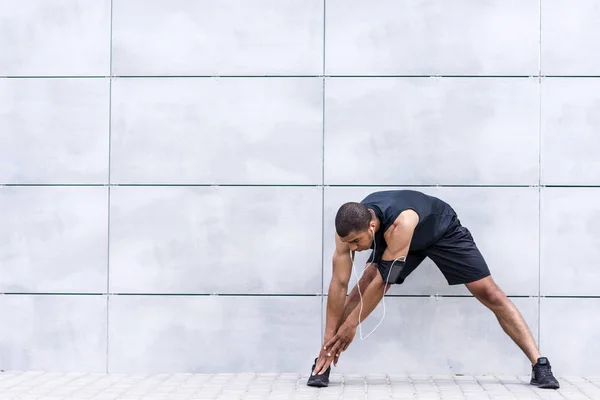 African american runner stretching on street — Stock Photo