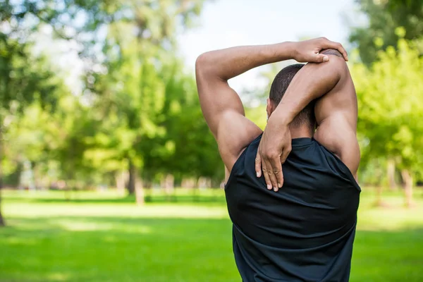 African american sportsman stretching in park — Stock Photo