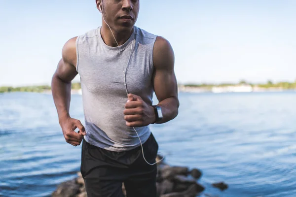 Deportista afroamericano corriendo a orillas del río - foto de stock