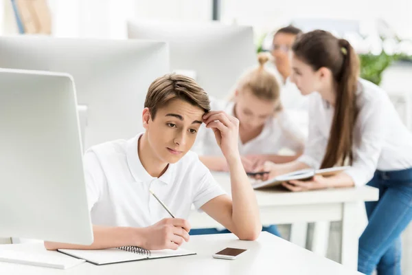 Pensive teenage boy in classroom — Stock Photo