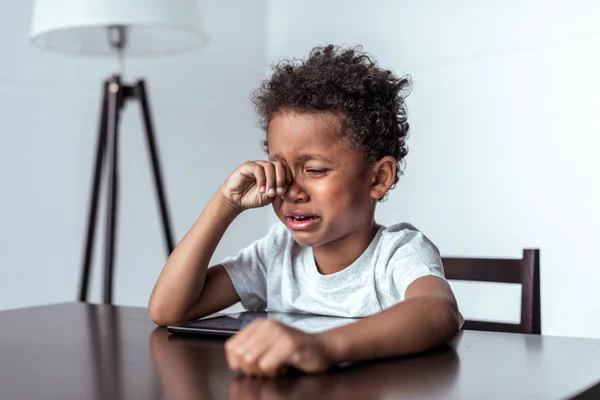 Мальчик плачет, сидя с табличкой — стоковое фото