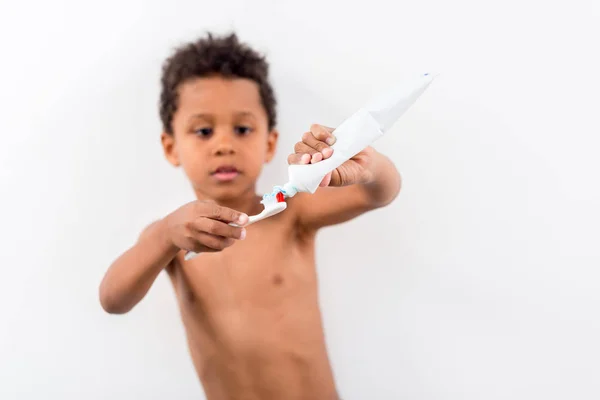 Kind trägt Zahnpasta auf Bürste auf — Stockfoto