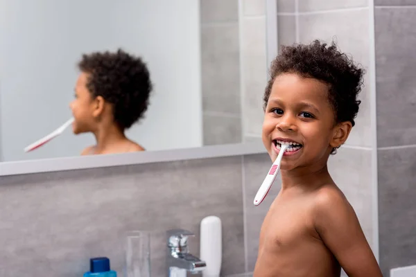 Afro niño cepillarse los dientes - foto de stock