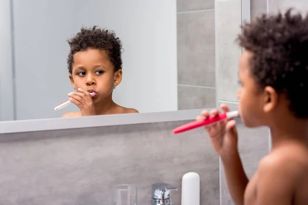Afro niño cepillarse los dientes - foto de stock