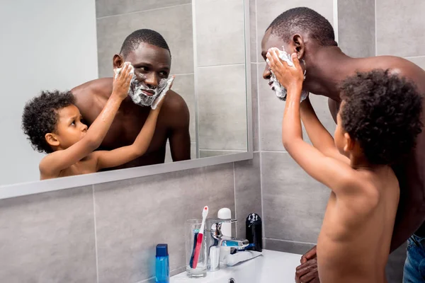 Son applying shaving foam on father — Stock Photo