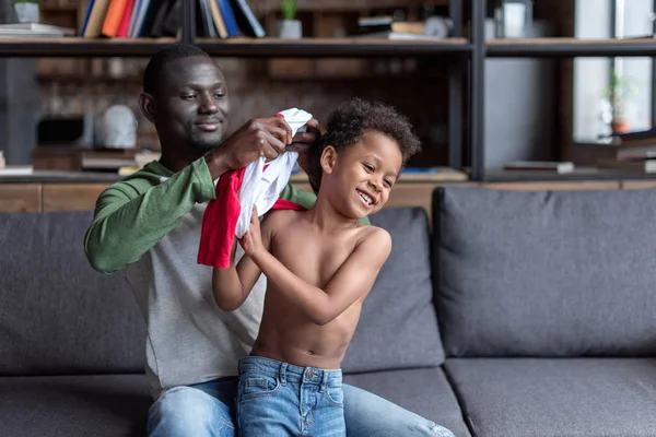 Padre vistiendo a su hijo - foto de stock