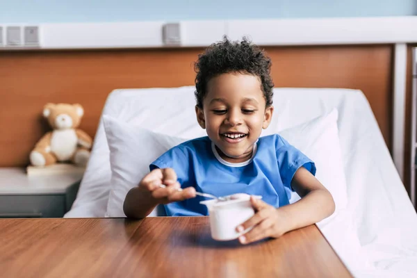 Niño afroamericano comiendo yogur - foto de stock
