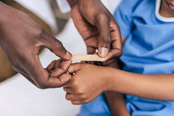 Africano médico americano colocando adesivo gesso — Fotografia de Stock