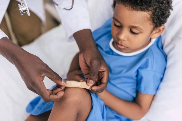 Africano médico americano colocando adesivo gesso — Fotografia de Stock