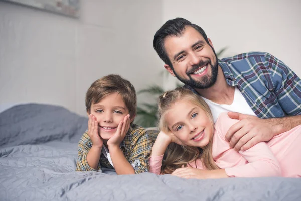 Padre e hijos descansando en la cama - foto de stock
