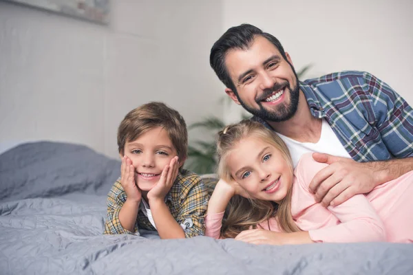 Pai e filhos descansando na cama — Fotografia de Stock