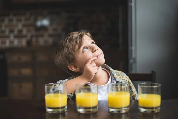 Kind am Tisch mit Gläsern Saft — Stockfoto