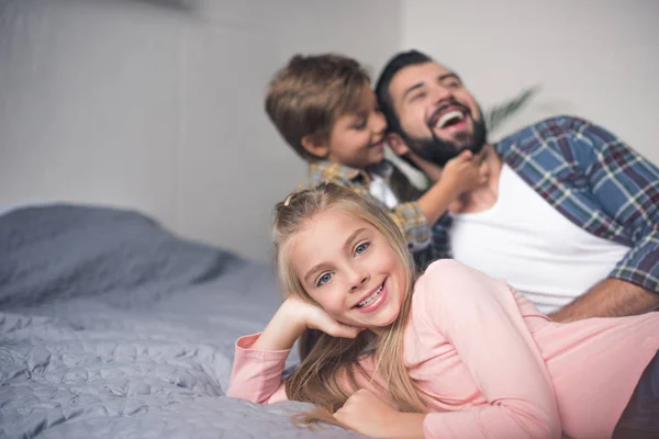 Padre e figli riposano sul letto — Foto stock