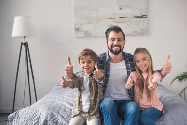 Padre e hijos mostrando pulgares hacia arriba - foto de stock