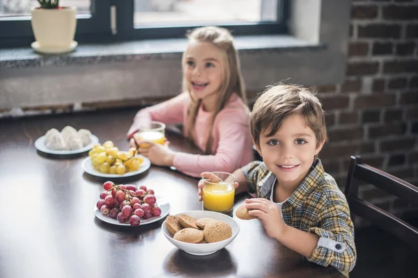 Frères et sœurs qui prennent le petit déjeuner à la maison — Photo de stock