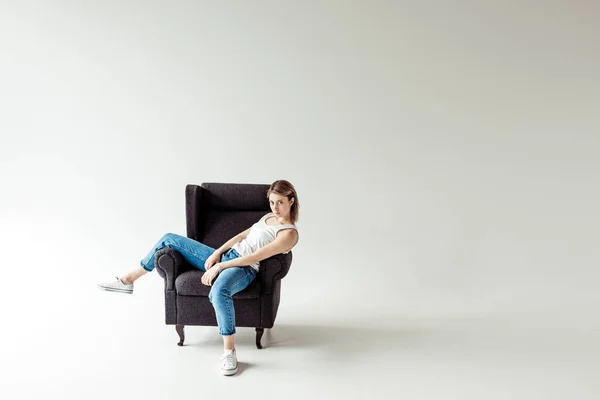 Woman in singlet sitting on armchair — Stock Photo