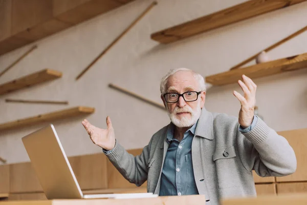 Bewildered senior man with laptop — Stock Photo