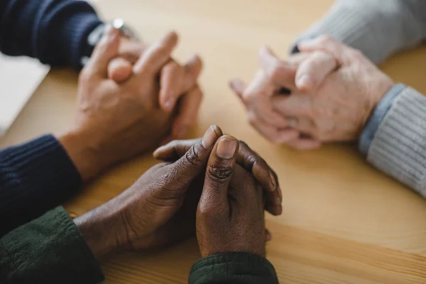 Hombres multiétnicos con las manos en la mesa - foto de stock