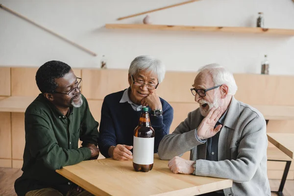Senior friends in bar with bottle of beer — Stock Photo