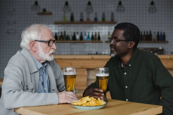 Amigos mayores hablando y bebiendo cerveza - foto de stock