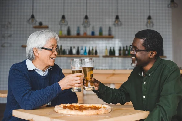 Senior friends clinking glasses of beer — Stock Photo