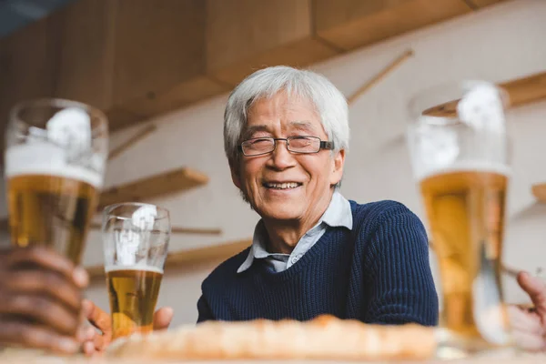 Senior asian man in bar with friends — Stock Photo