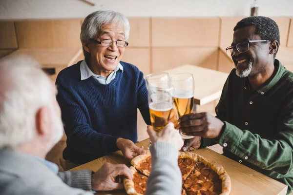 Senior friends clinking glasses of beer — Stock Photo
