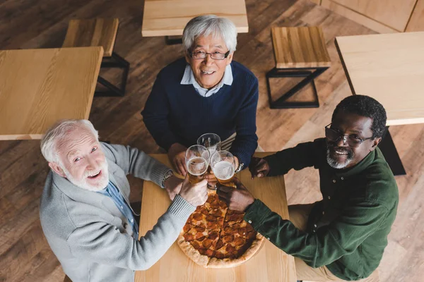 Senior friends clinking glasses of beer — Stock Photo