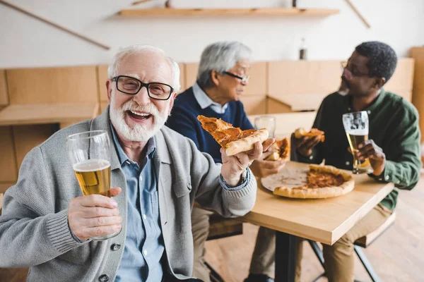 Uomo anziano mangiare pizza con birra — Foto stock