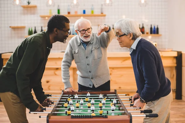 Amis seniors jouant au baby-foot — Photo de stock