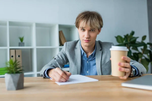 Бизнесмен держит кофе в бумажной чашке — стоковое фото