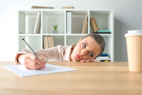 Tired businesswoman lying on table — Stock Photo