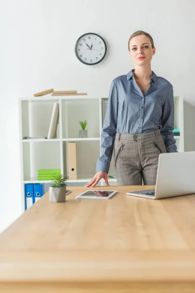 Бізнес-леді стоїть за робочим столом — стокове фото
