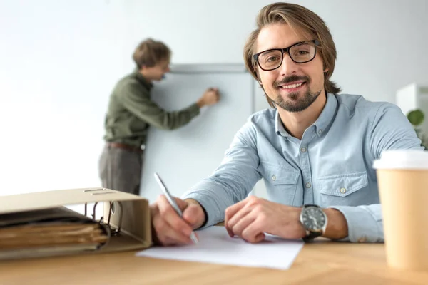 Smiling businessman sitting at table — Stock Photo