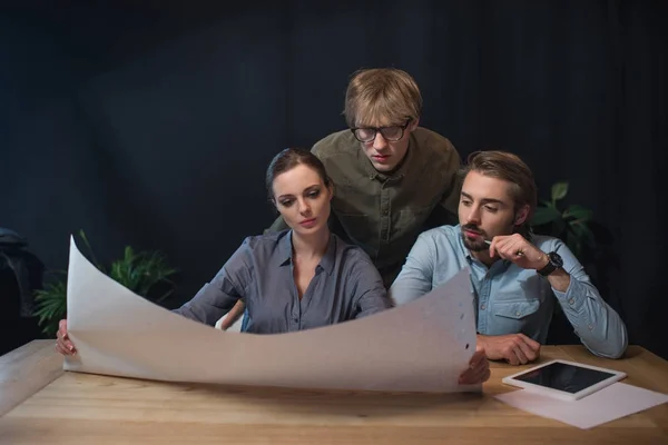 Businesspeople looking at flipchart paper — Stock Photo