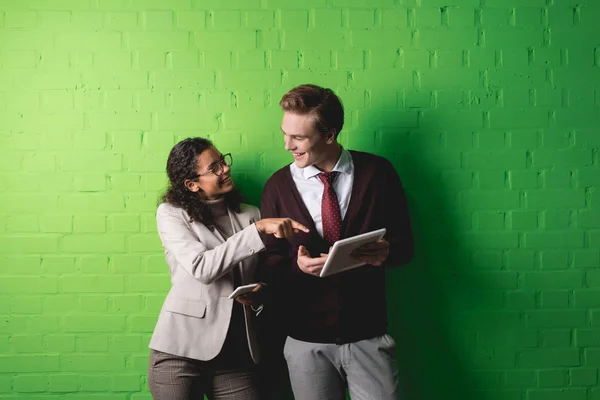 Multiethnische Geschäftsleute arbeiten mit digitalem Tablet und Smartphone vor grüner Wand — Stockfoto