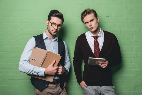 Jeunes hommes d'affaires travaillant avec tablette numérique et documents devant le mur vert — Photo de stock