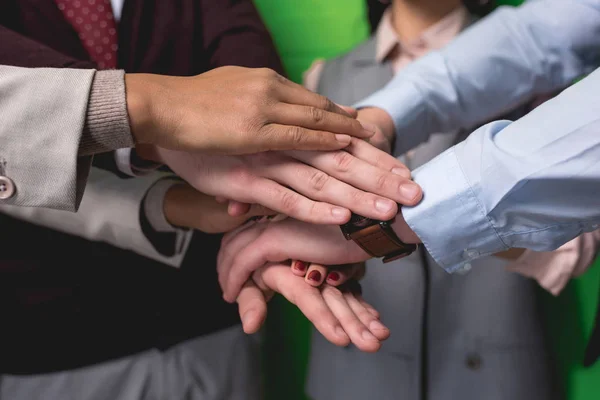 Ausgeschnittene Ansicht eines Geschäftsteams, das sich vor grüner Wand die Hände hält — Stockfoto