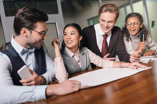 Cheerful multiethnic businesspeople working with digital devices and documents in office — Stock Photo