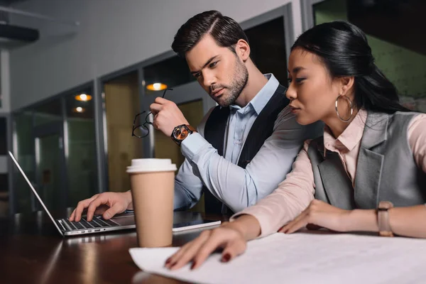 Businessman and asian businesswoman working together with laptop and documents in office — Stock Photo