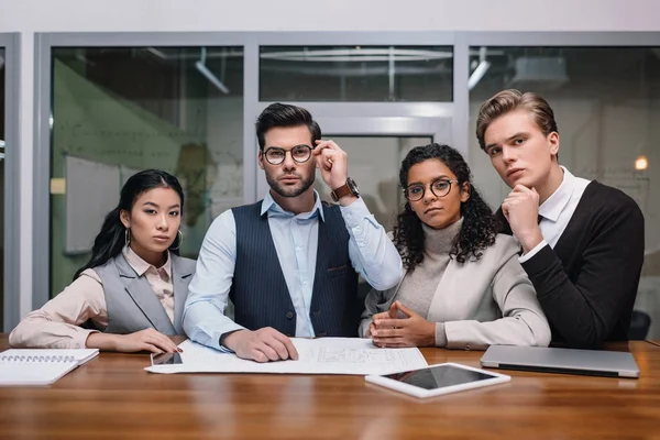 Fokussierte multikulturelle Geschäftsleute, die im Büro mit digitalen Geräten und Dokumenten arbeiten — Stockfoto