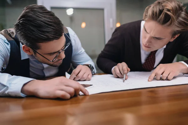 Businessmen working together with blueprint in office — Stock Photo