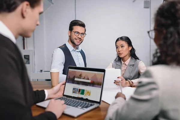 Equipo empresarial multiétnico con documentos y portátil con shutterstock sitio web - foto de stock