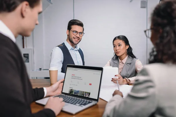 Multiethnic business team with documents and laptop with airbnb website — Stock Photo