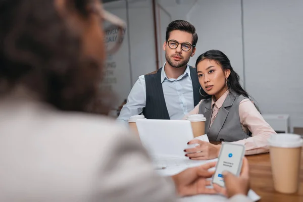 Multiethnic businesspeople working together with tablet and smartphone with facebook messenger appliance — Stock Photo