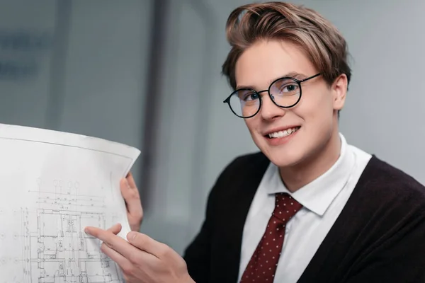Jeune homme d'affaires souriant dans les lunettes de travail avec le plan — Photo de stock